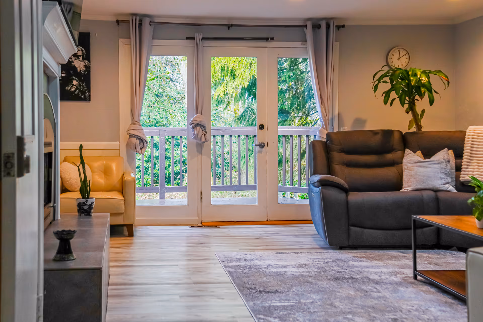 Bright living room with a dark gray sofa, plant, and glass balcony doors.