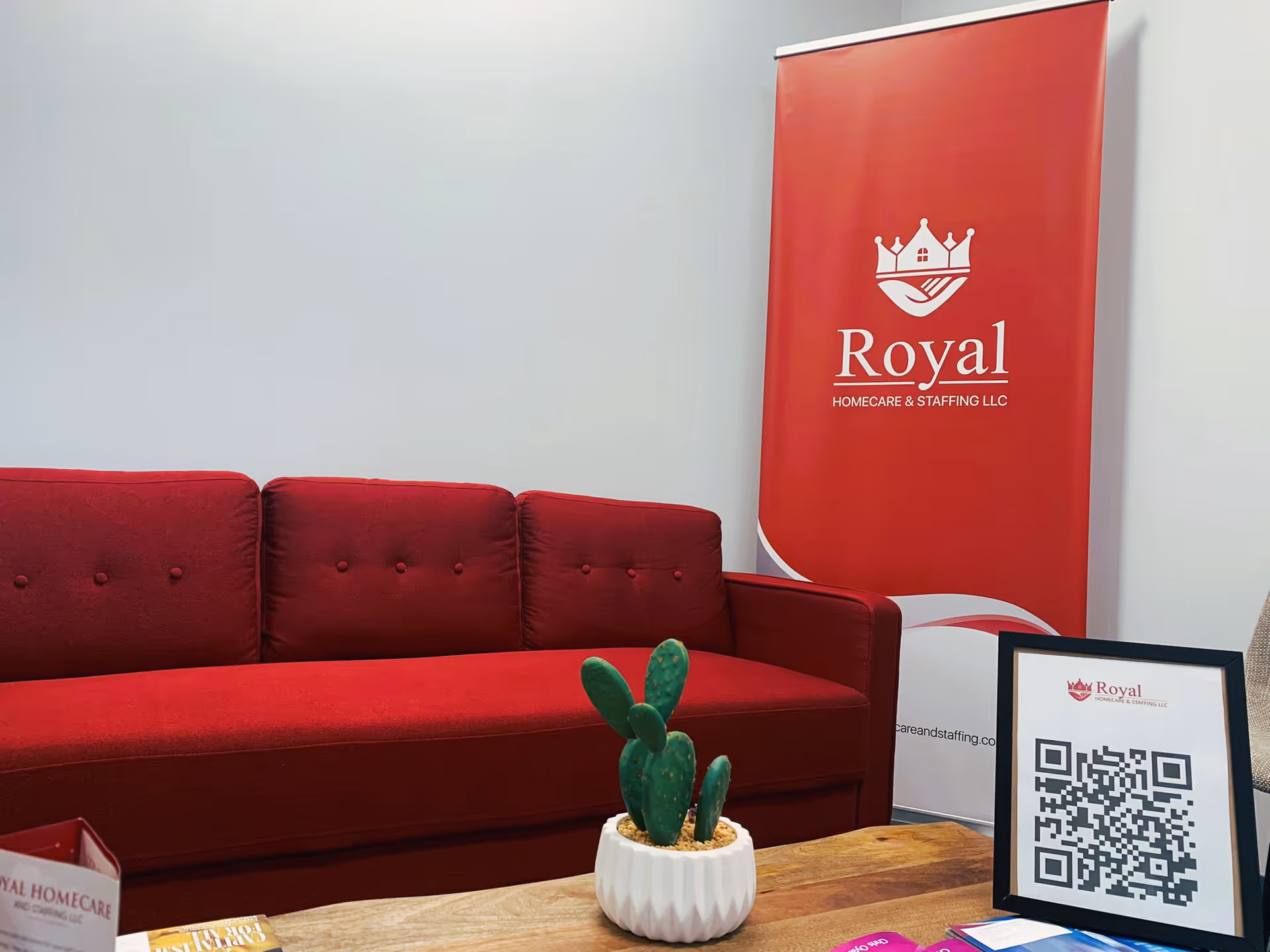 Red sofa, Royal banner, cactus planter, and QR frame in a reception area.