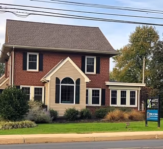 Two-story brick building with a manicured lawn and a Right at Home sign