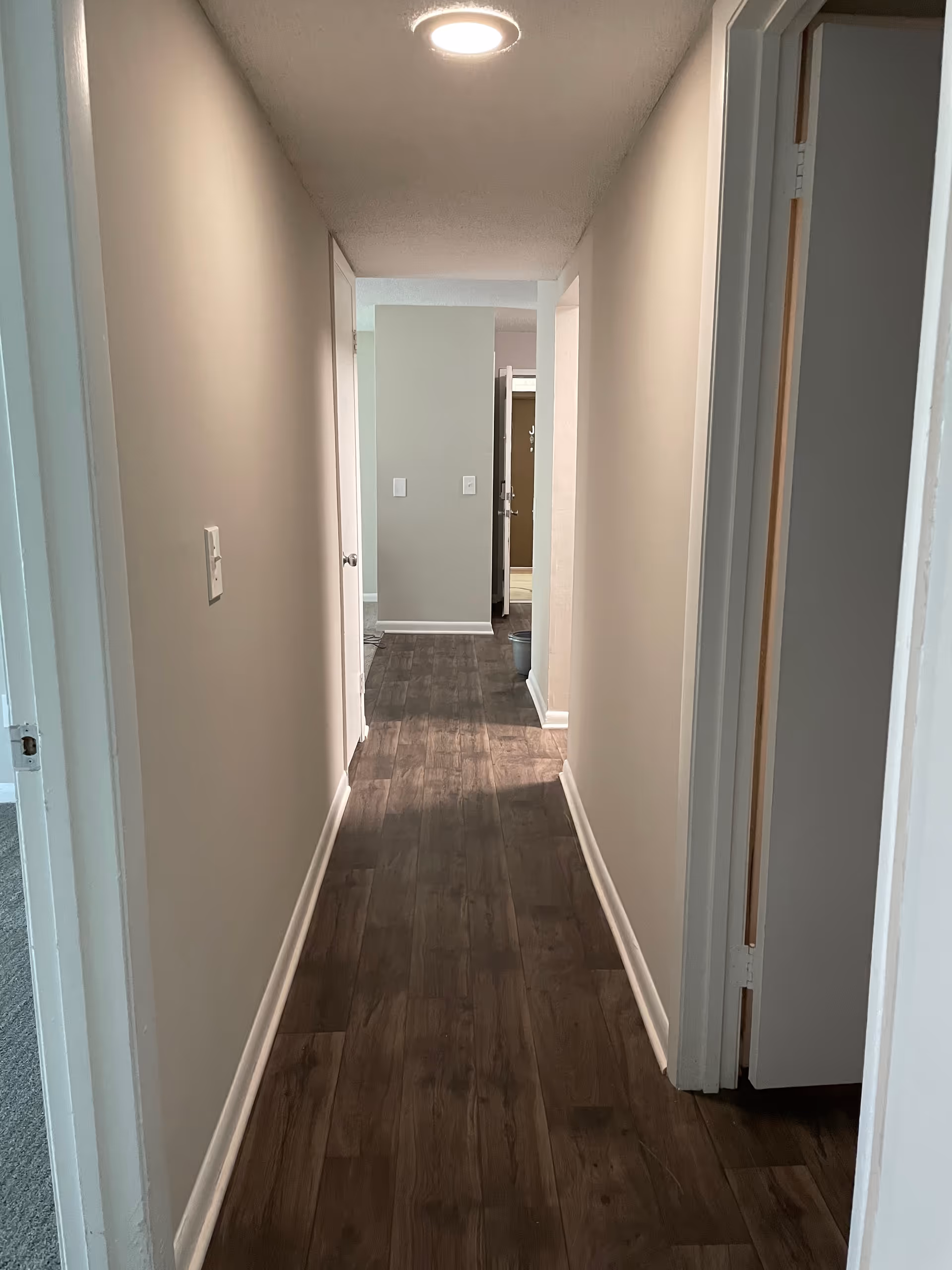 A bright, narrow hallway in a senior living facility with doors.