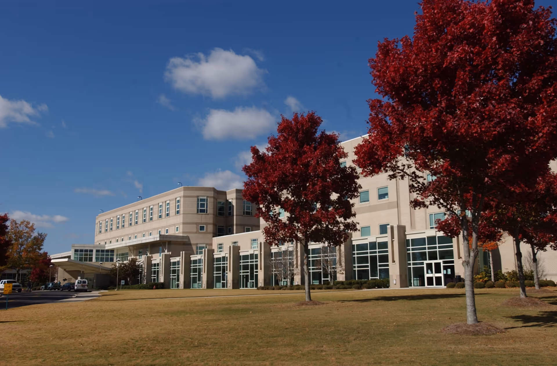 Exterior view of Cullman Regional Medical Center with glass windows and red autumn trees.