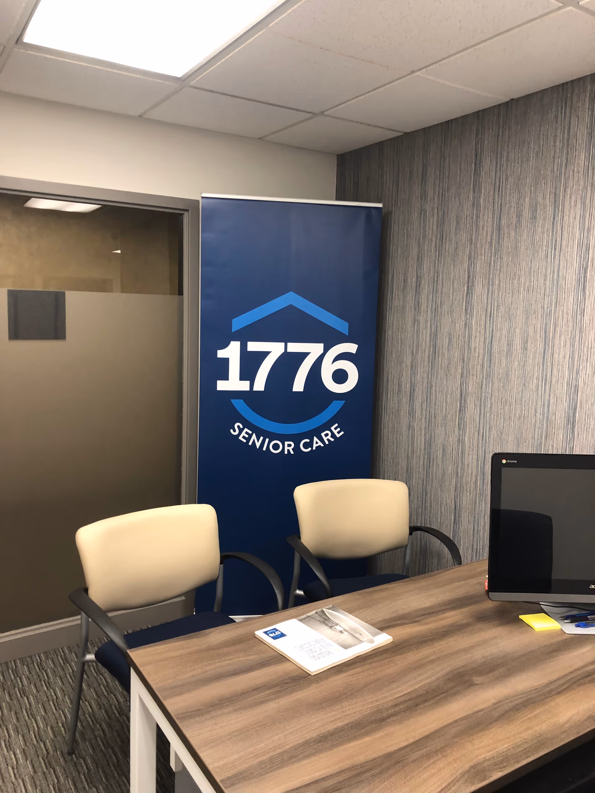 Reception area with a 1776 Senior Care banner, desk, computer, and two chairs.