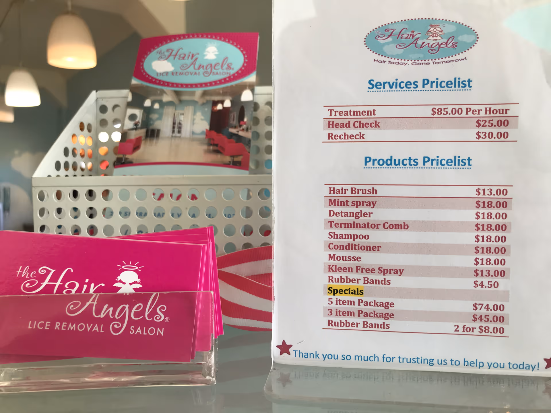 Bright pink business cards and a price list in a salon window.