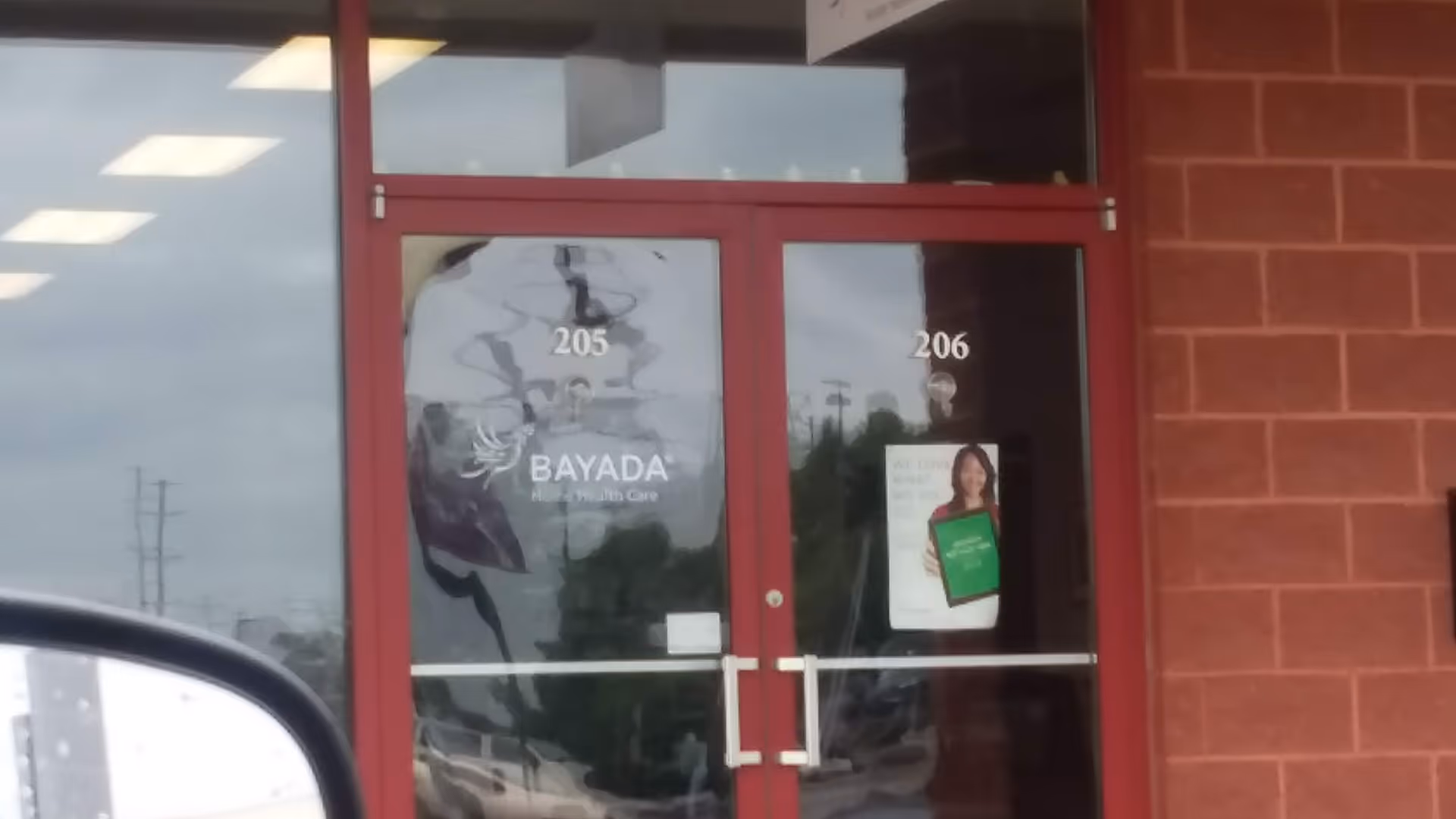 Red-framed glass doors with BAYADA signage at a brick exterior entrance.