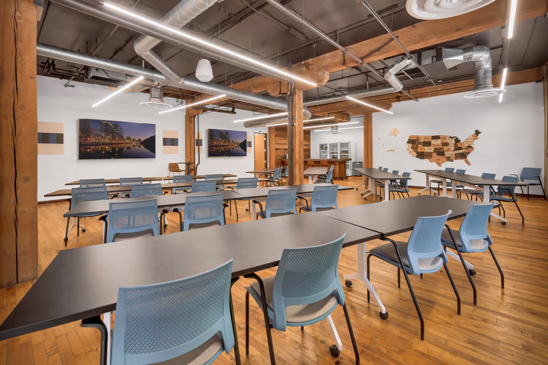 Open multipurpose training room with long tables, blue chairs, and exposed ductwork.