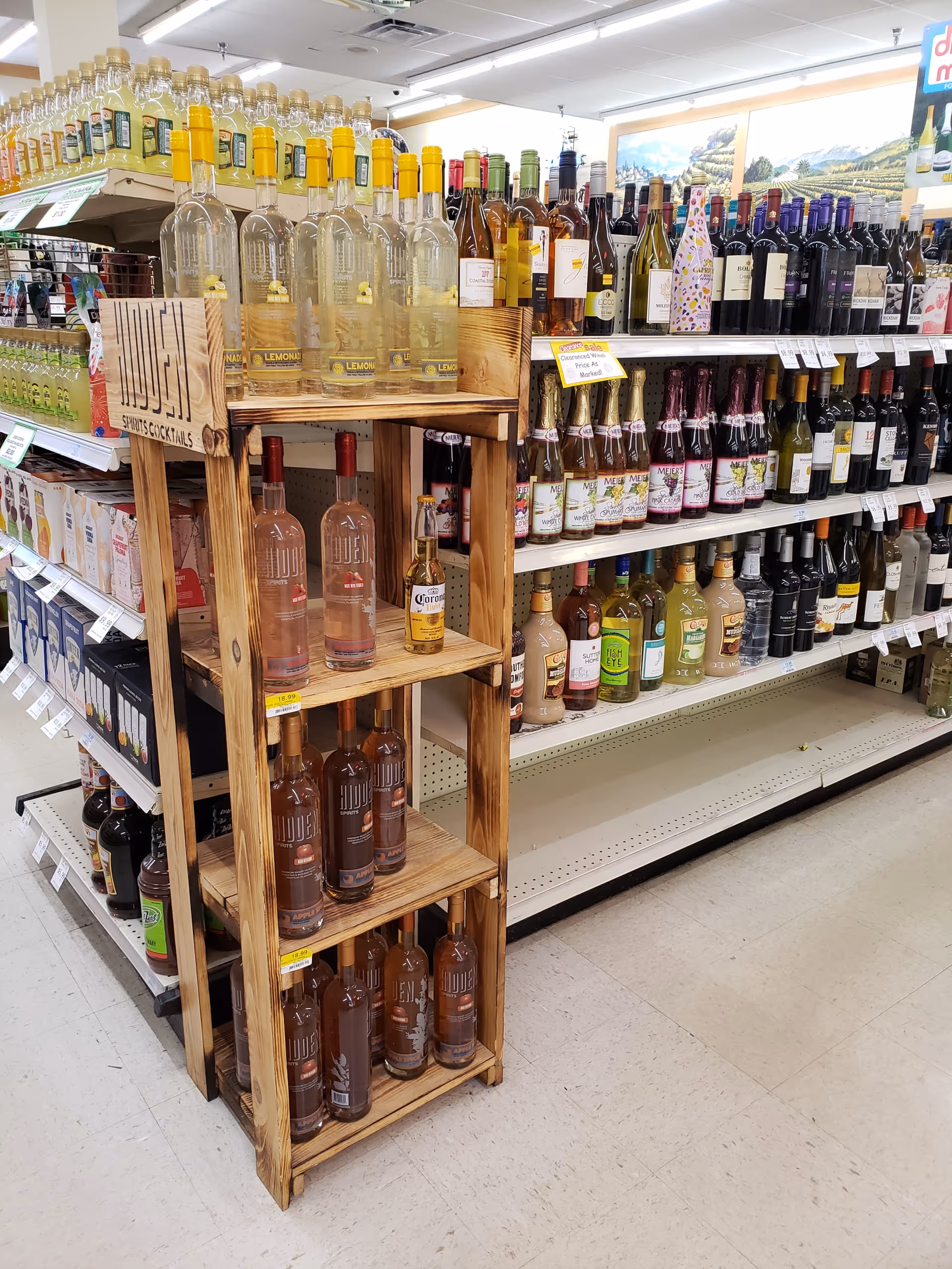 Liquor aisle with wooden display and numerous bottle racks inside Discount Drug Mart.