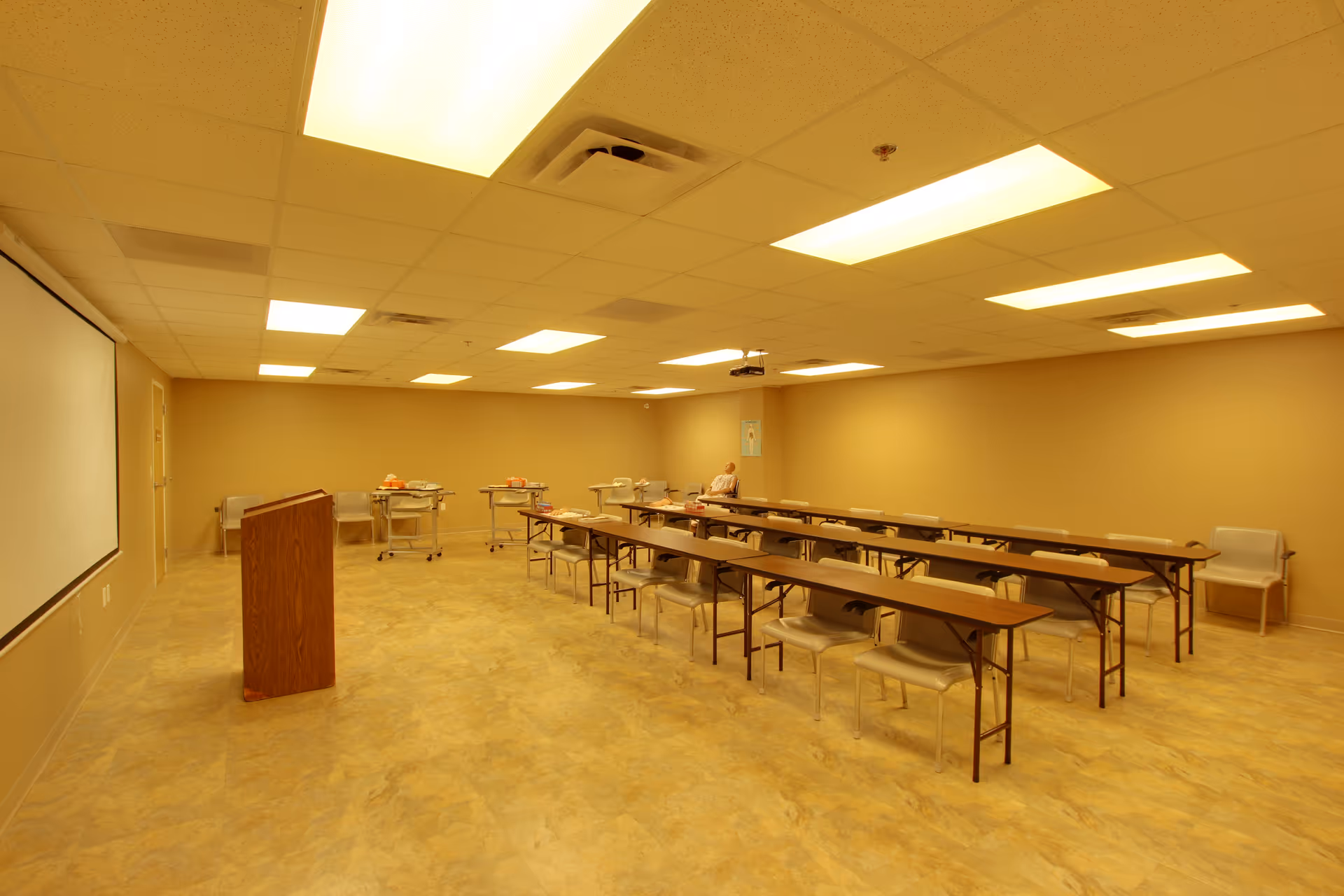 A classroom-style meeting room in a senior living facility with long tables and chairs.