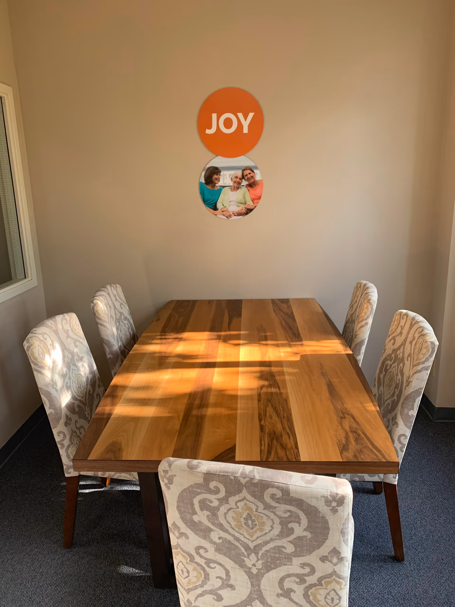 Bright dining area with a wooden table and patterned upholstered chairs.