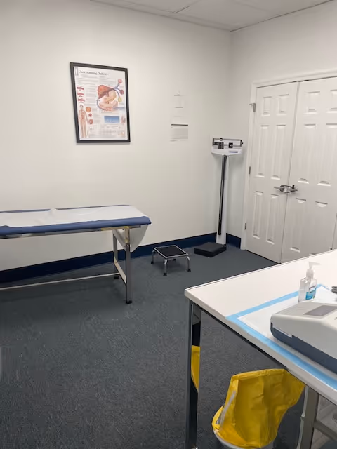 Exam room with an examination table, scale, step stool, and chart on the wall.