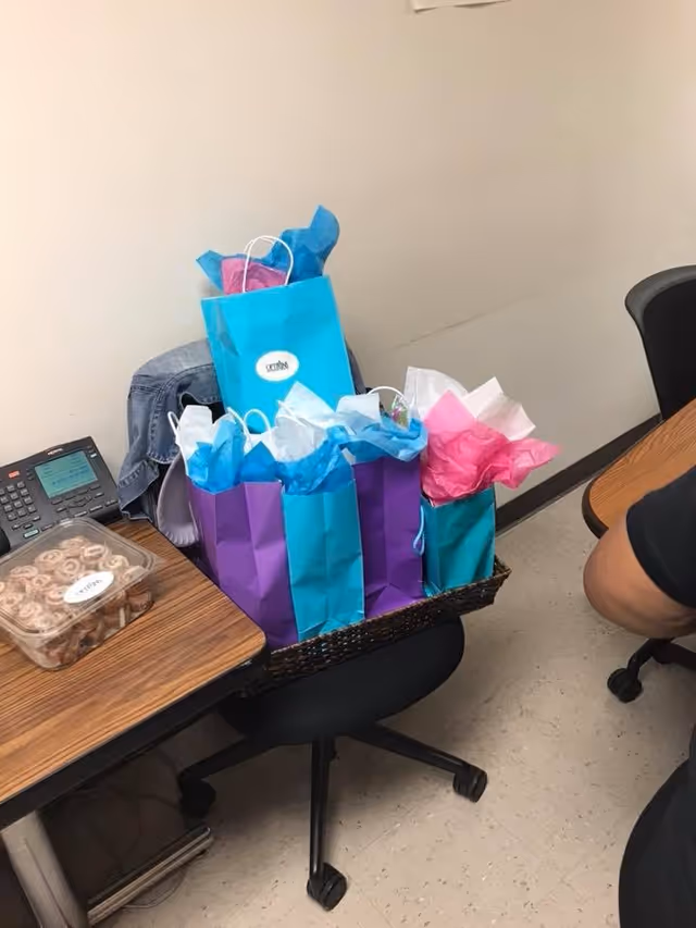 Table with colorful gift bags and tissue paper in an office-like senior facility room.