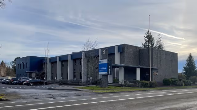 Exterior view of a PeaceHealth Southwest Hospice building with parked cars.