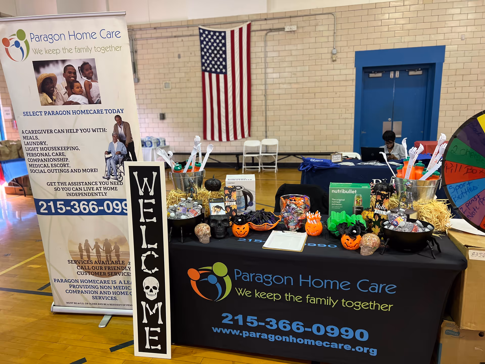 Paragon Home Care booth at indoor event with banners, a table, and an American flag.