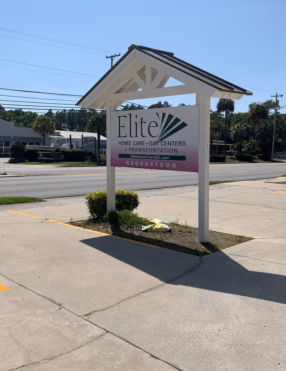 Exterior view of a facility sign for Elite Home Care Day Centers by a road.