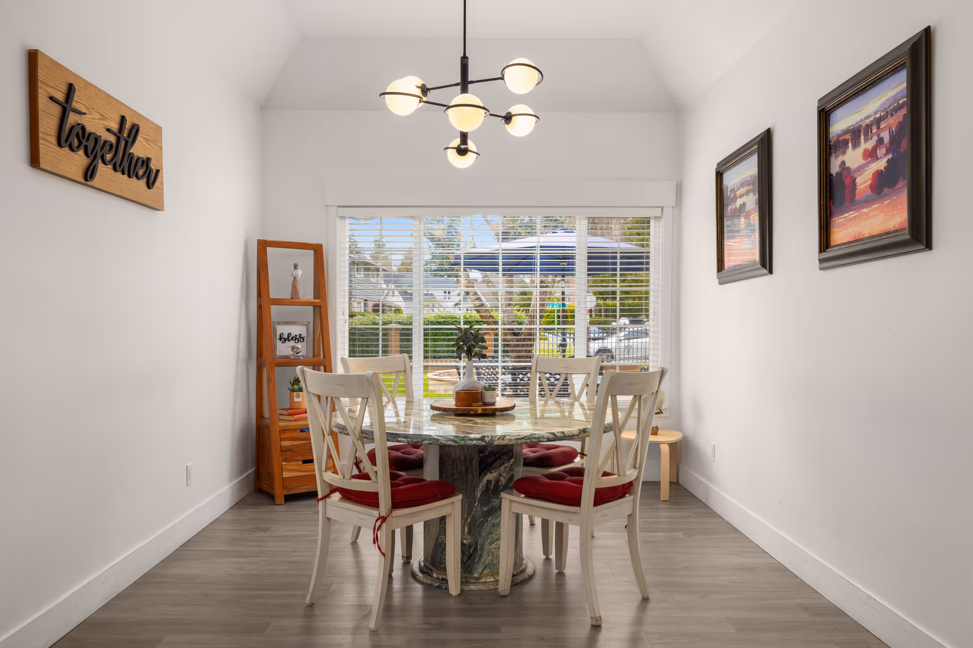 Bright dining room with round marble table, white chairs, and large window.