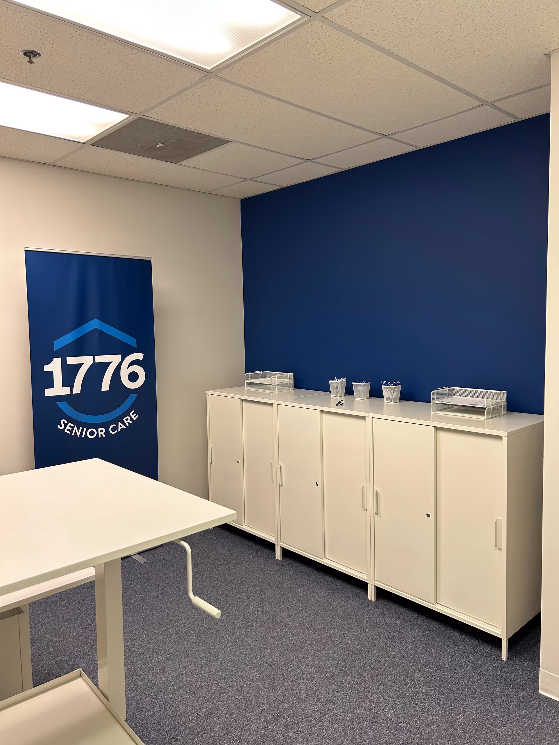 Interior room with white cabinets, blue wall, banner reading 1776 Senior Care.