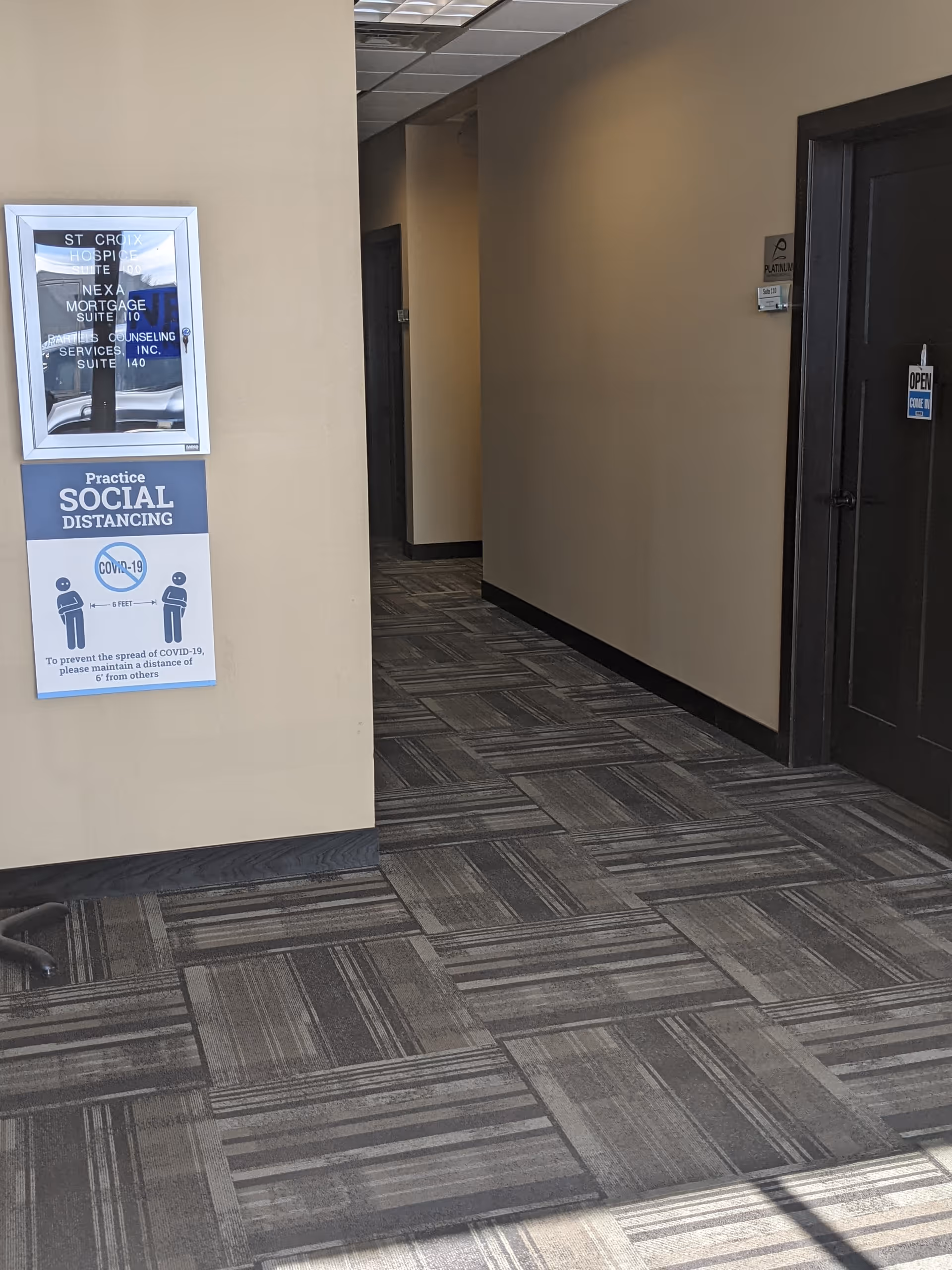 A hallway inside St. Croix Hospice with social distancing signage on beige walls.