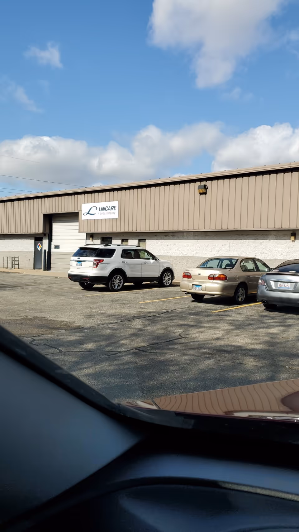 Exterior view of a LINCARE facility with parked cars in the lot.