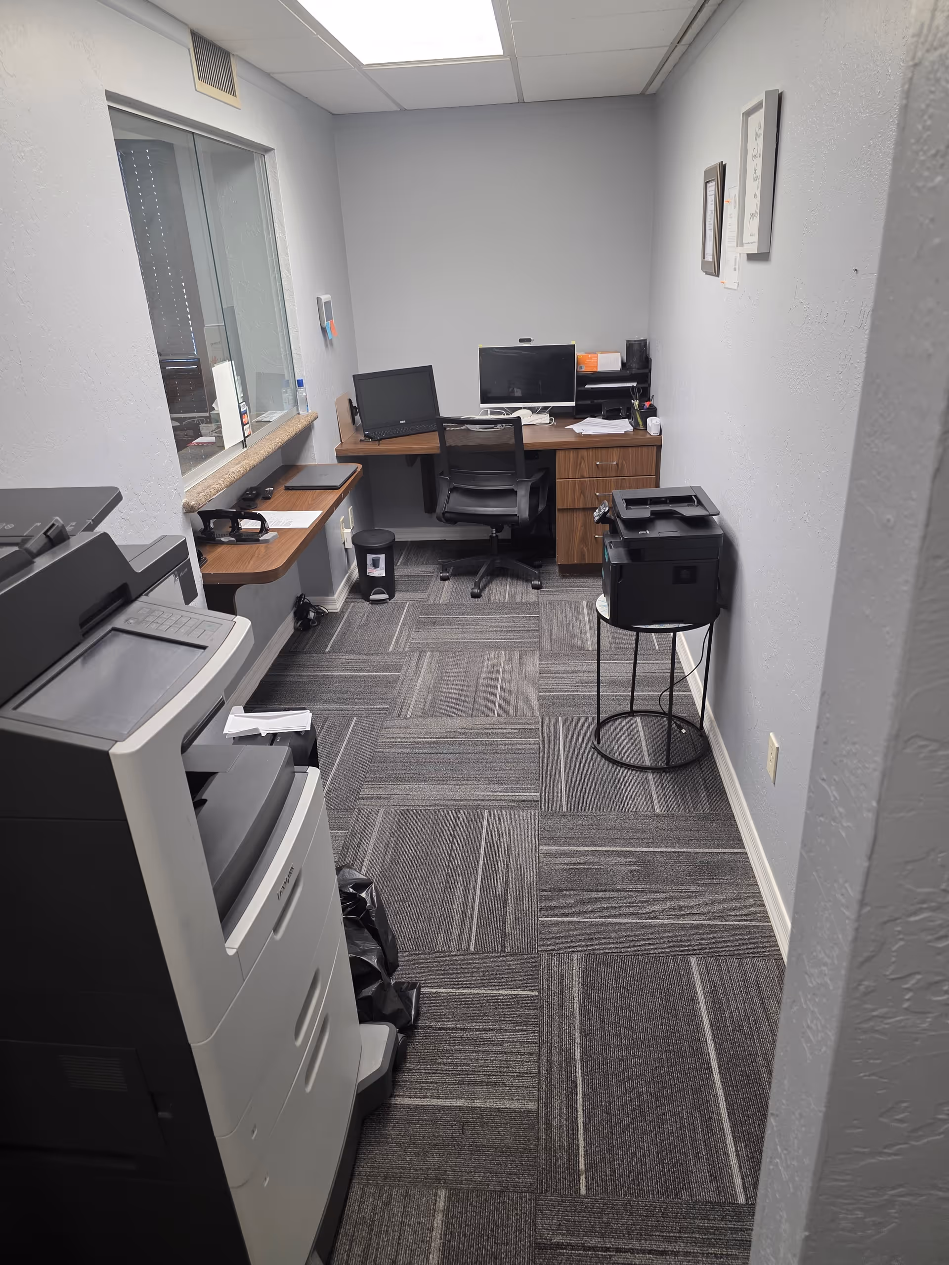 Small office in a facility with desk, computer, and printer.