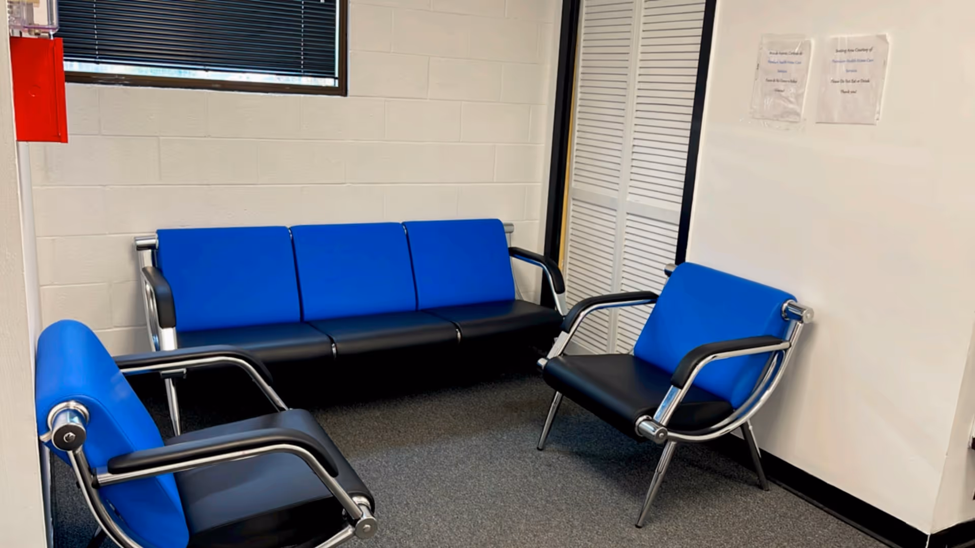 Blue cushioned chairs arranged in a small waiting lounge inside a facility.