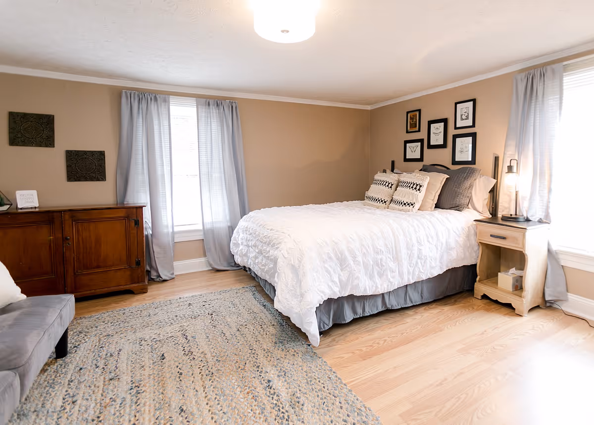 A cozy bedroom featuring a large bed, nightstands, and soft decor.
