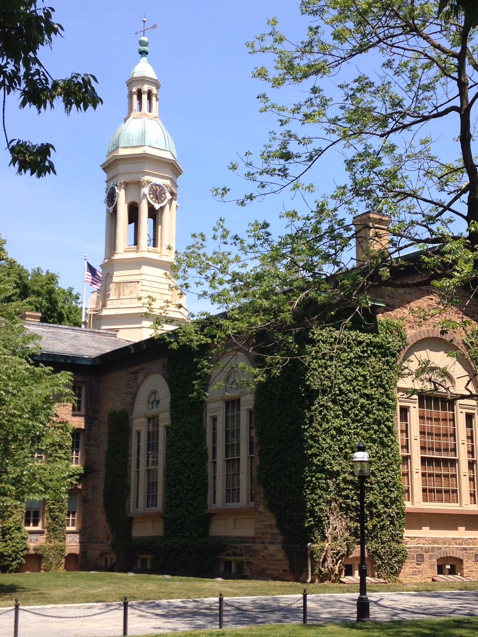 Ivy-covered brick building with a tall clock tower against a blue sky.