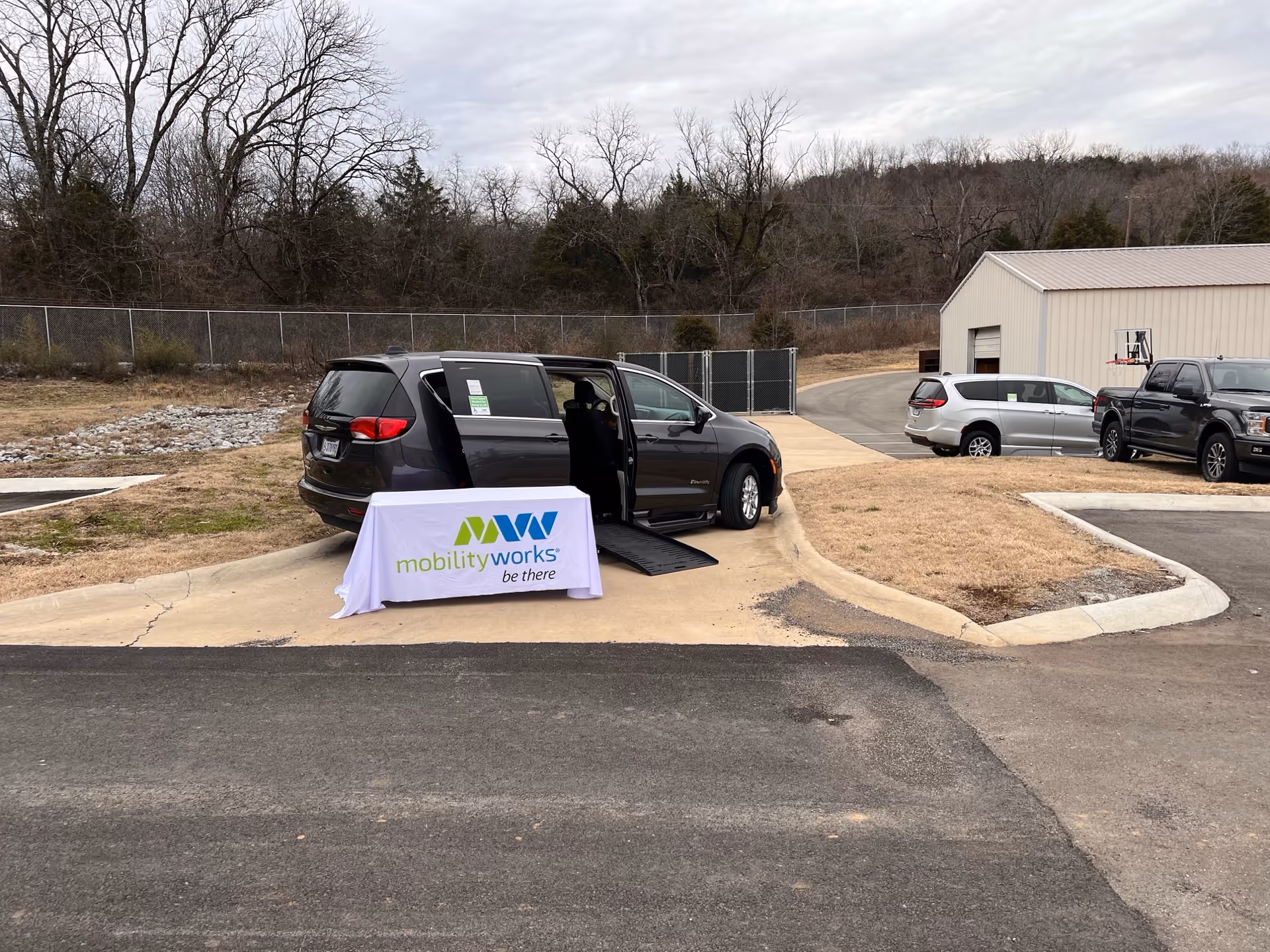 MobilityWorks van with ramp extended beside a table outside a facility.
