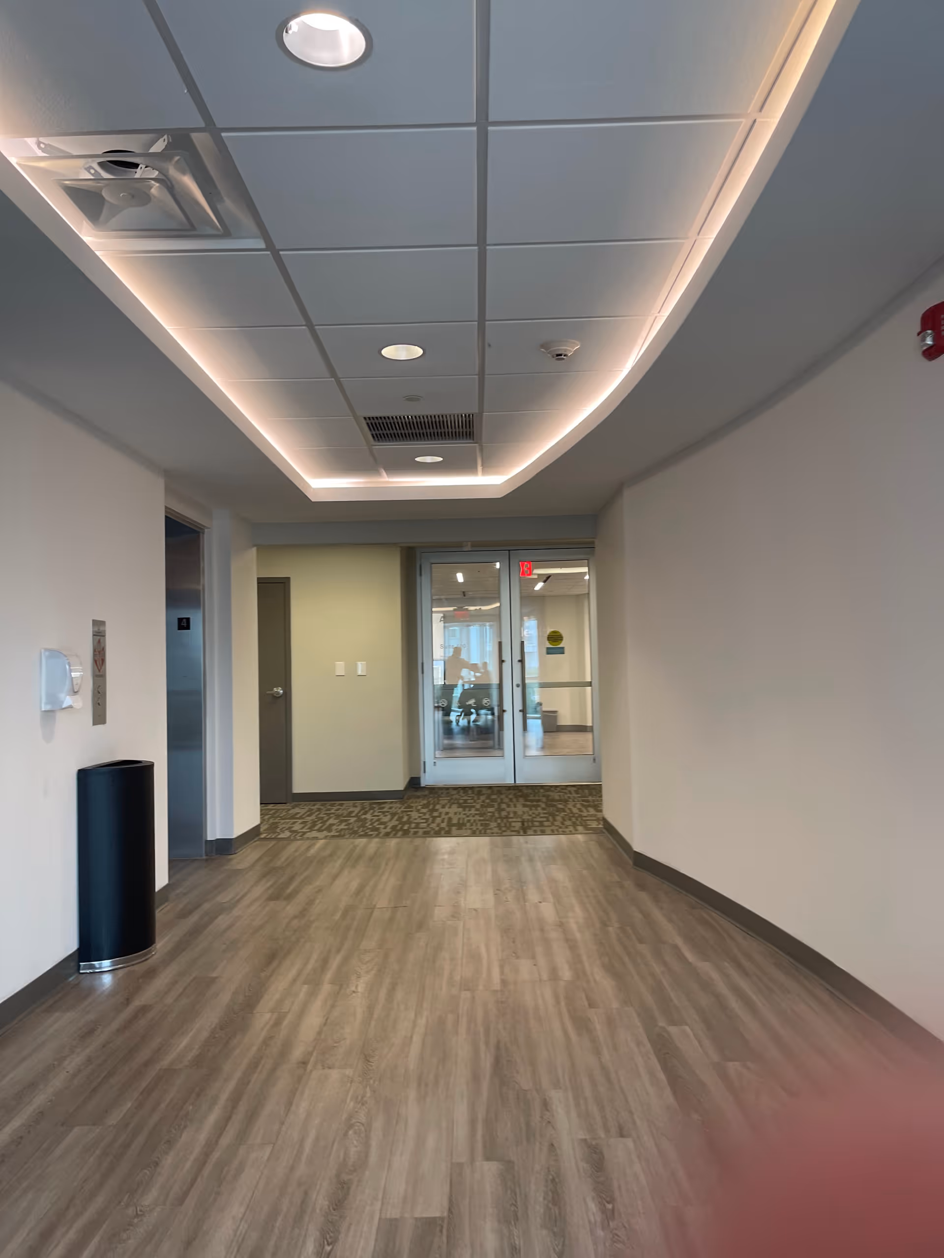 Long hallway inside a modern senior living facility with ceiling lights.