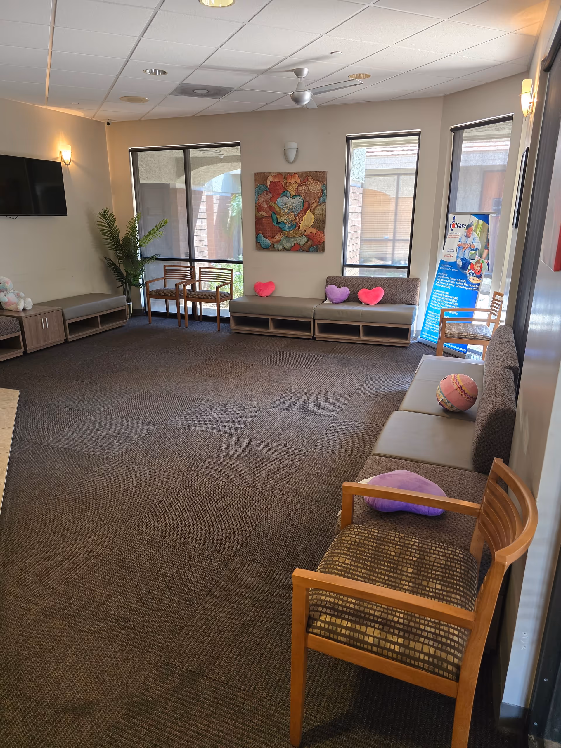 A cozy indoor lounge with couches, chairs, and heart cushions in a senior living facility.