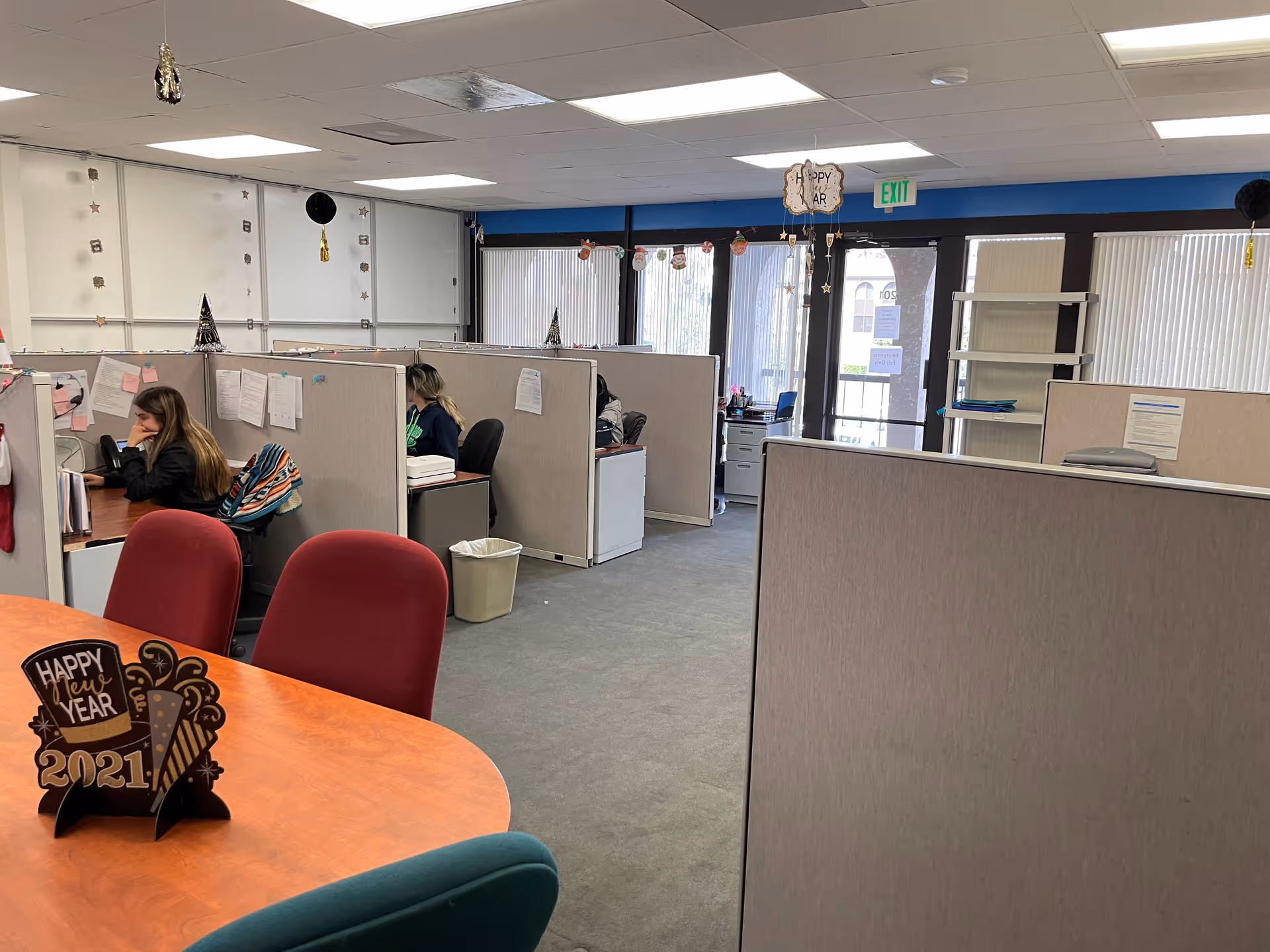 Office cubicles with staff working at desks in a shared workspace.