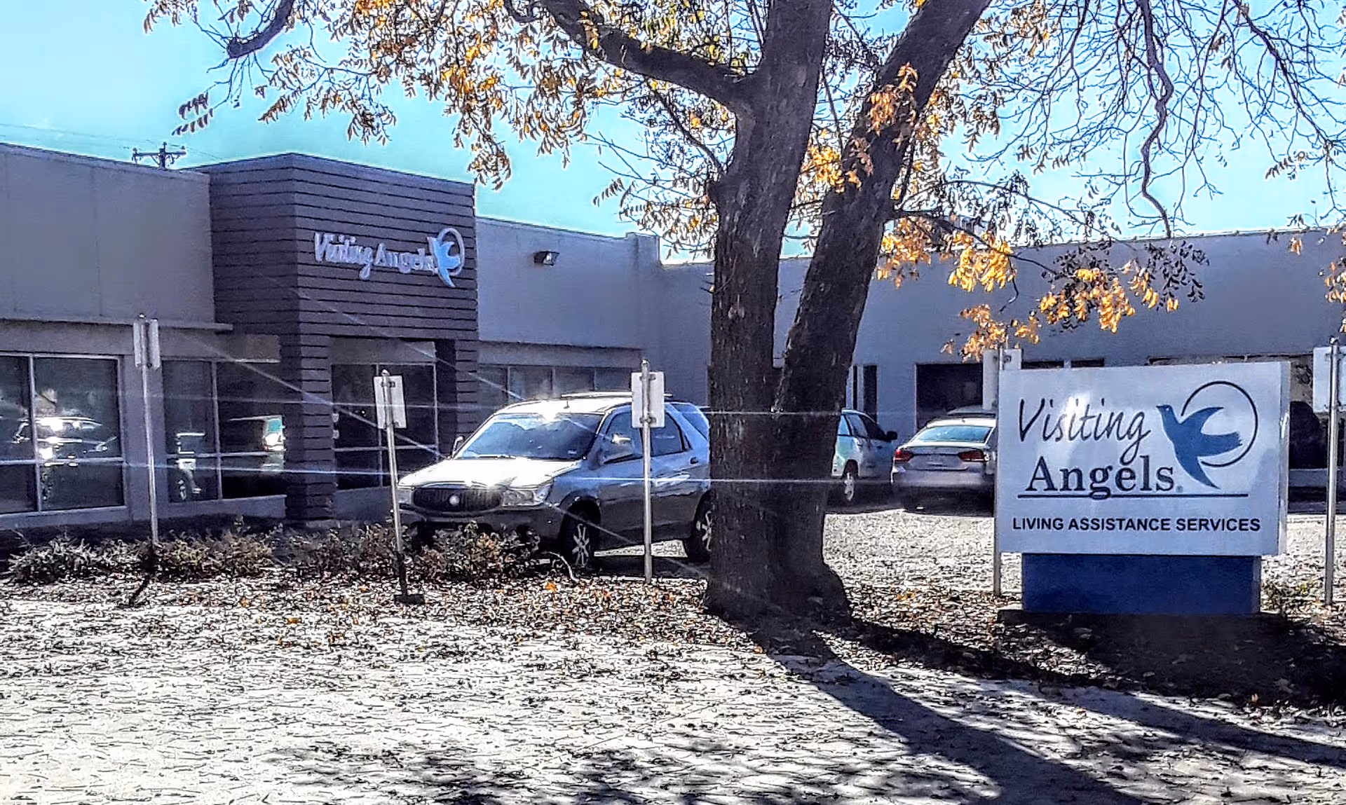 Exterior of Visiting Angels senior home care building with a sign and parked cars.