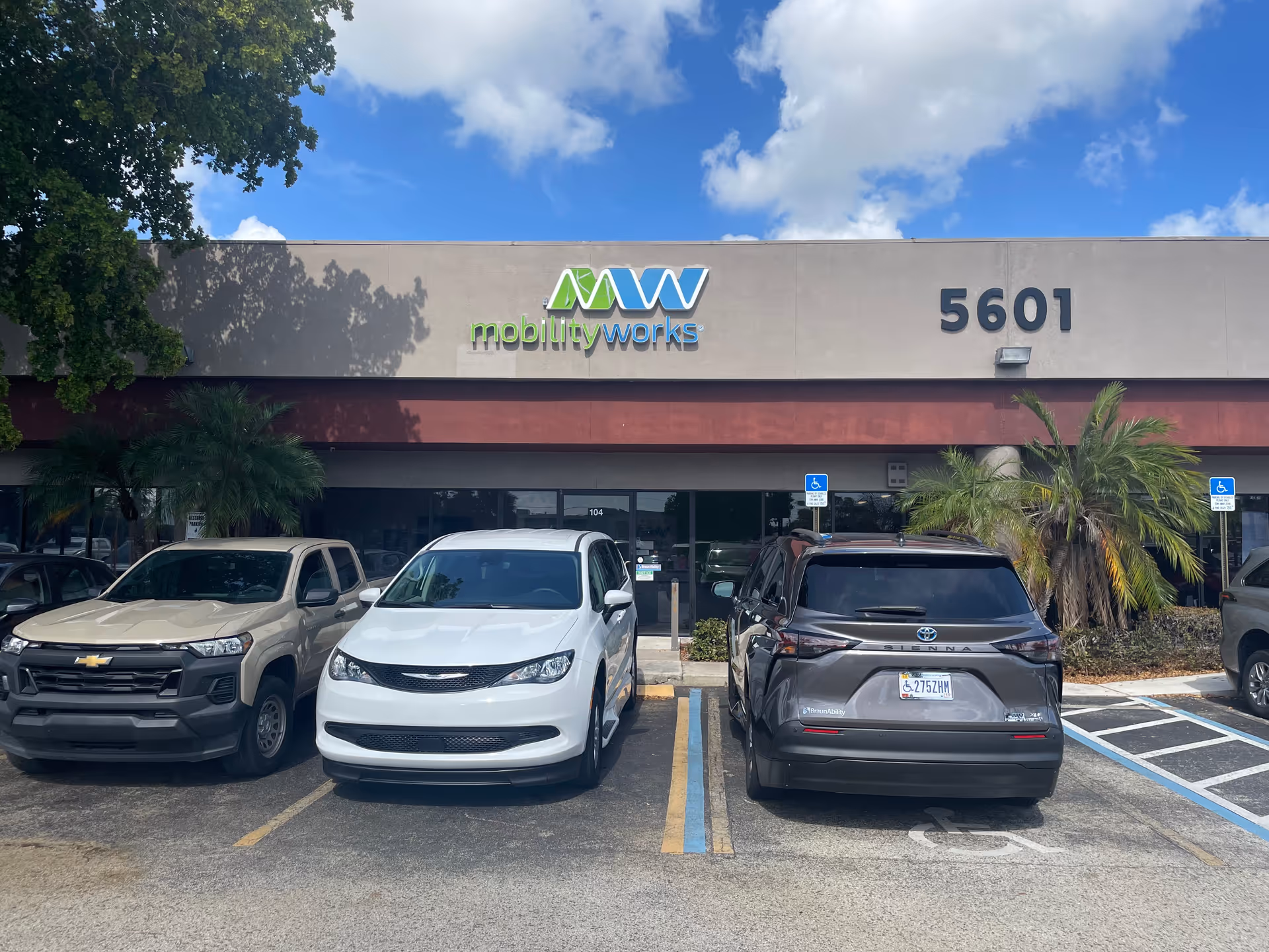 Front of MobilityWorks building with logo, address 5601, and parked cars.