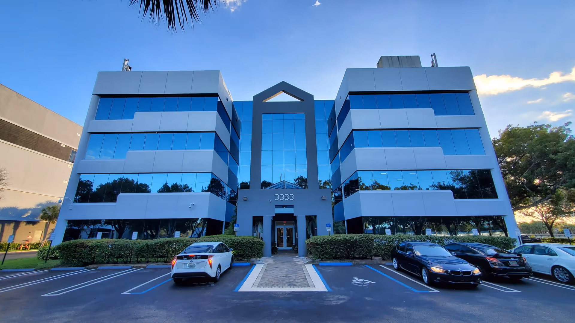 Modern glass-front building with central entry and front parking area