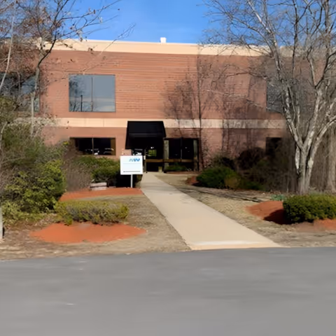 Exterior brick senior living building with a central walkway and surrounding trees.