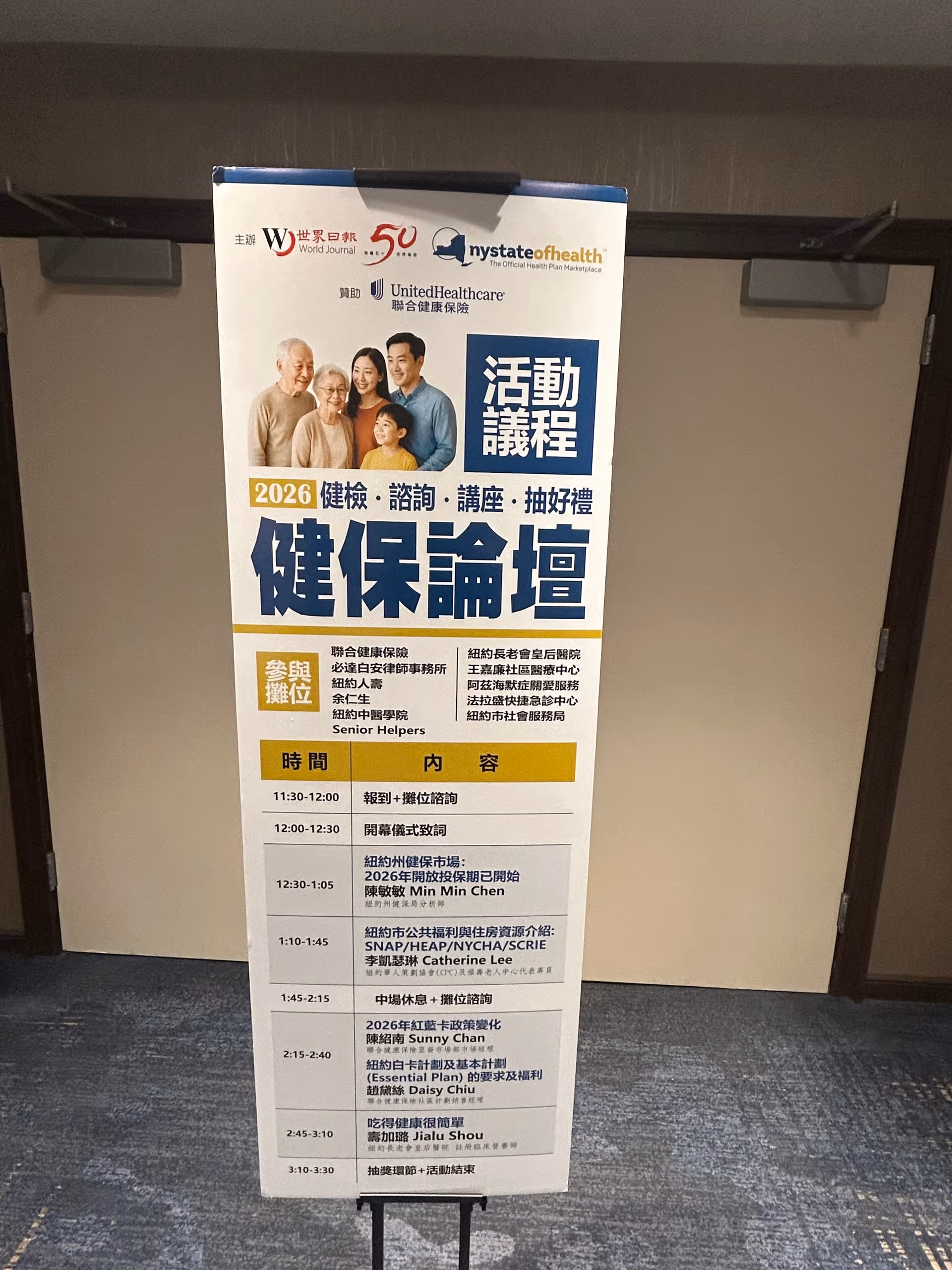 Tall vertical event poster on a stand in a hallway featuring people images and Chinese text.