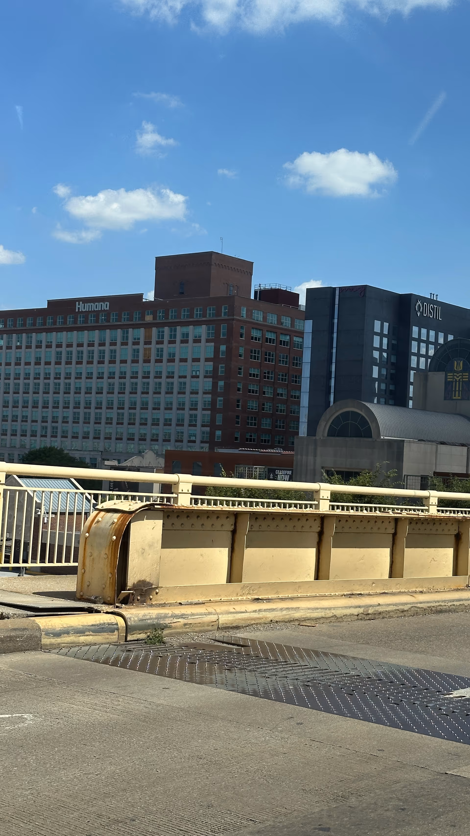 Urban street scene with a sidewalk, railing, and tall office buildings under blue sky.