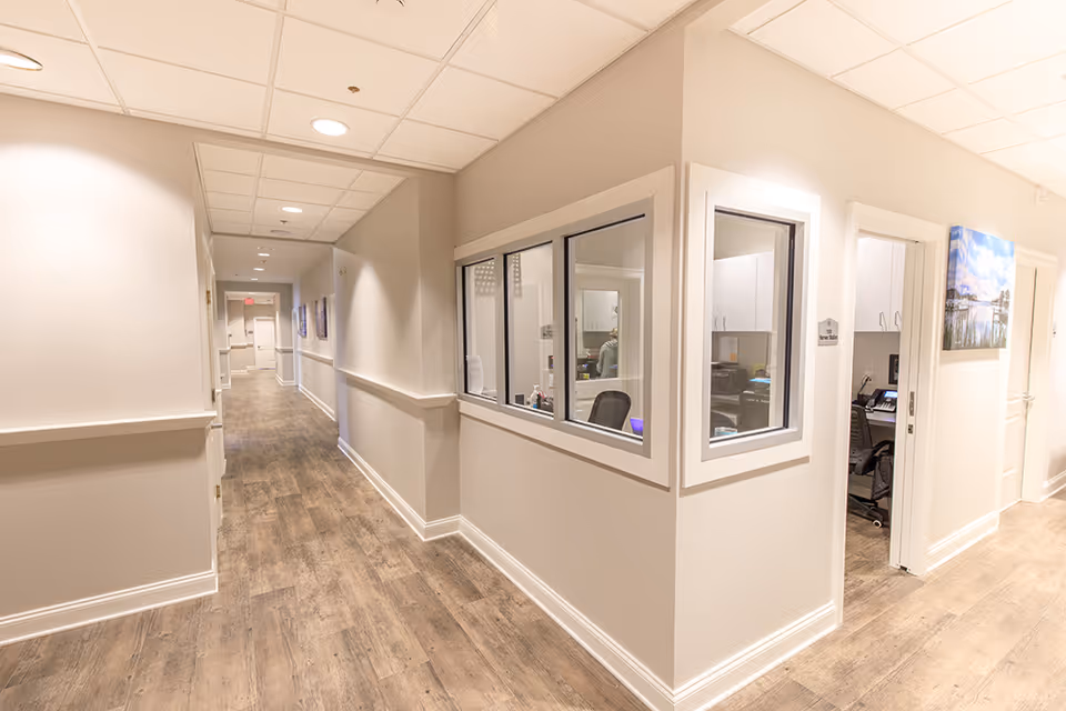 Bright interior hallway at Compass senior living facility with office windows and doors.