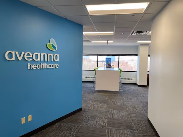 Blue wall with Aveanna Healthcare logo and a reception desk in a bright interior hallway.