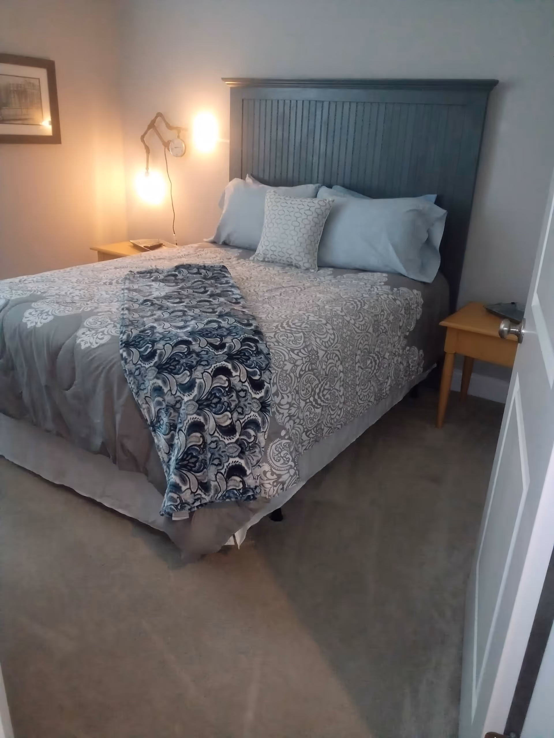 A tidy bedroom with a large bed, headboard, pillows, and bedside tables.