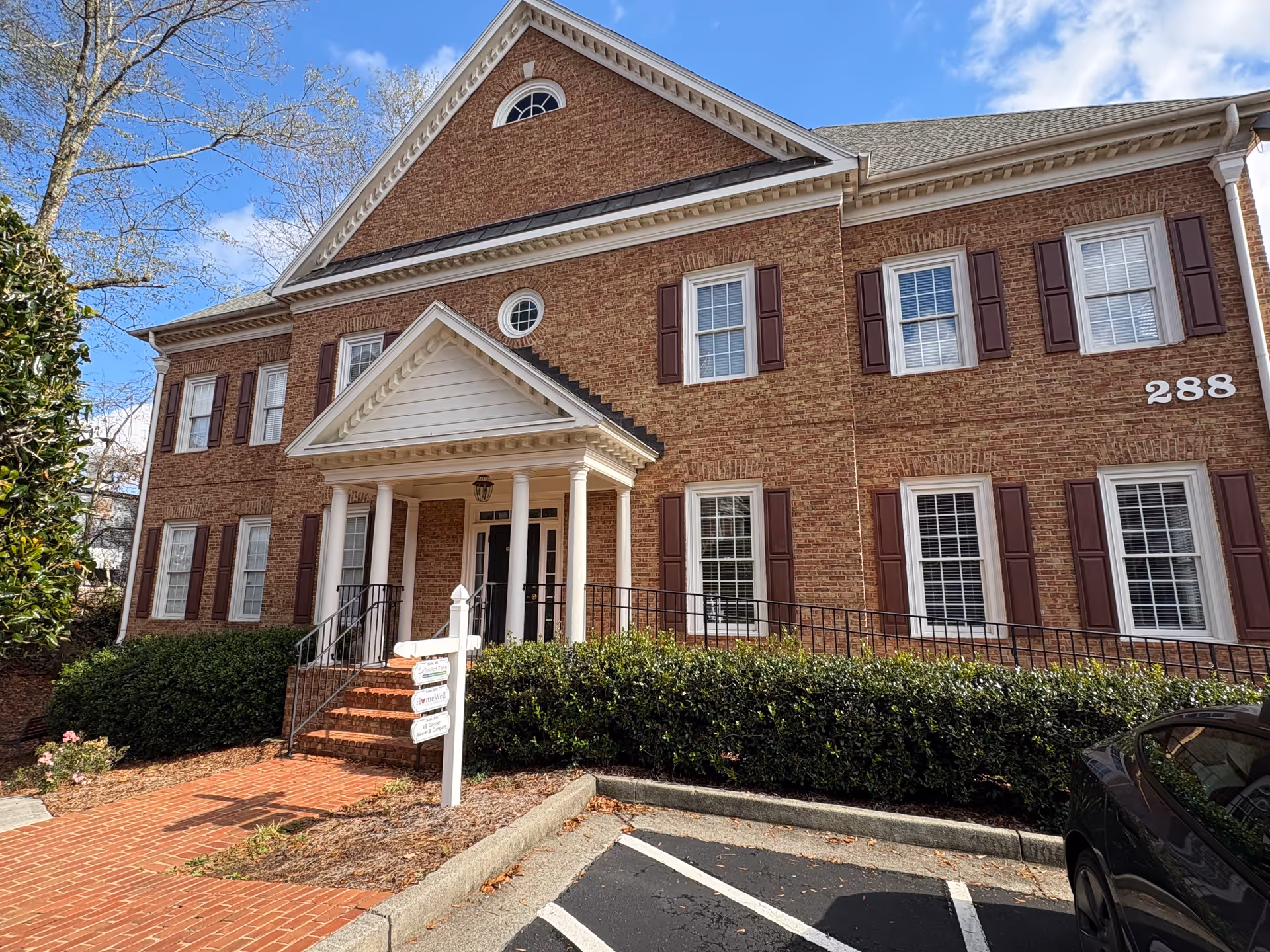 Front view of a brick senior living facility with white columns and steps.