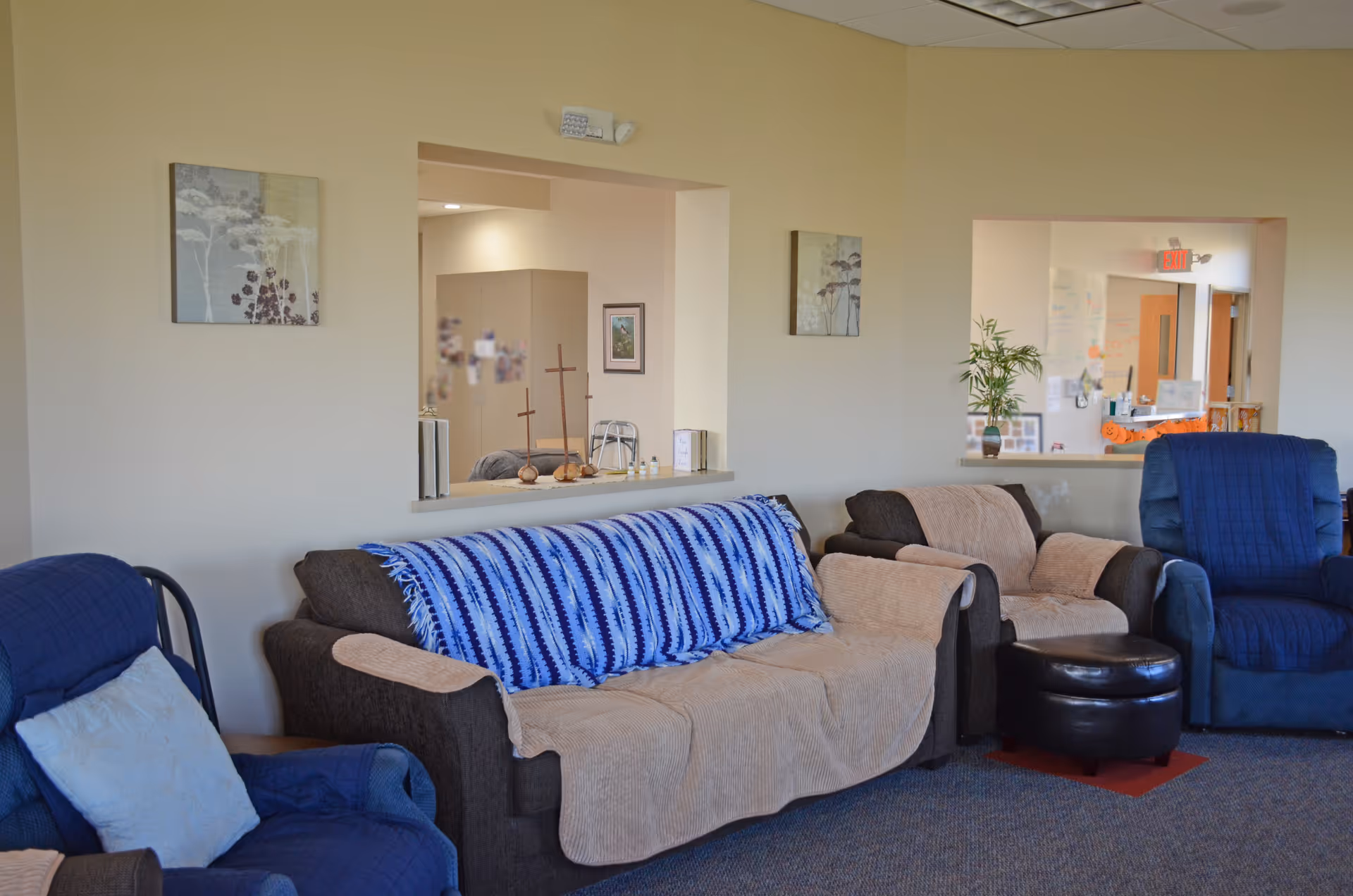 Cozy senior living lounge with blue seating, couches, and a striped throw blanket.