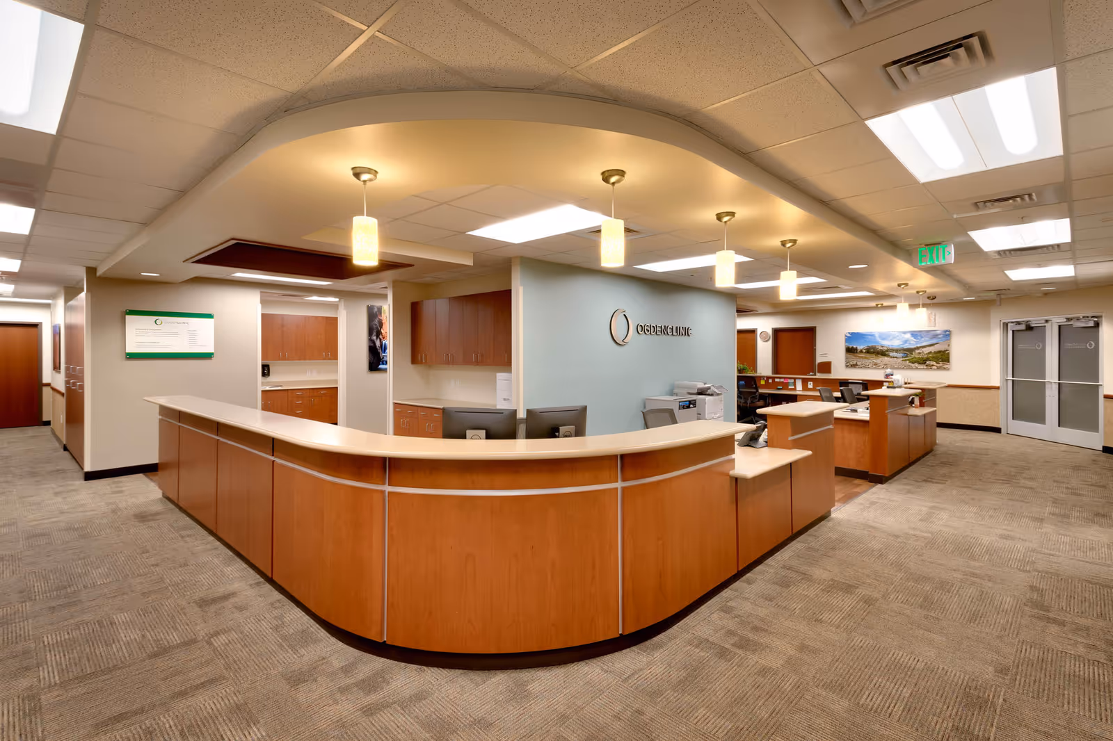 Curved wooden reception desk in a spacious clinic lobby with signage reading Ogden Clinic.