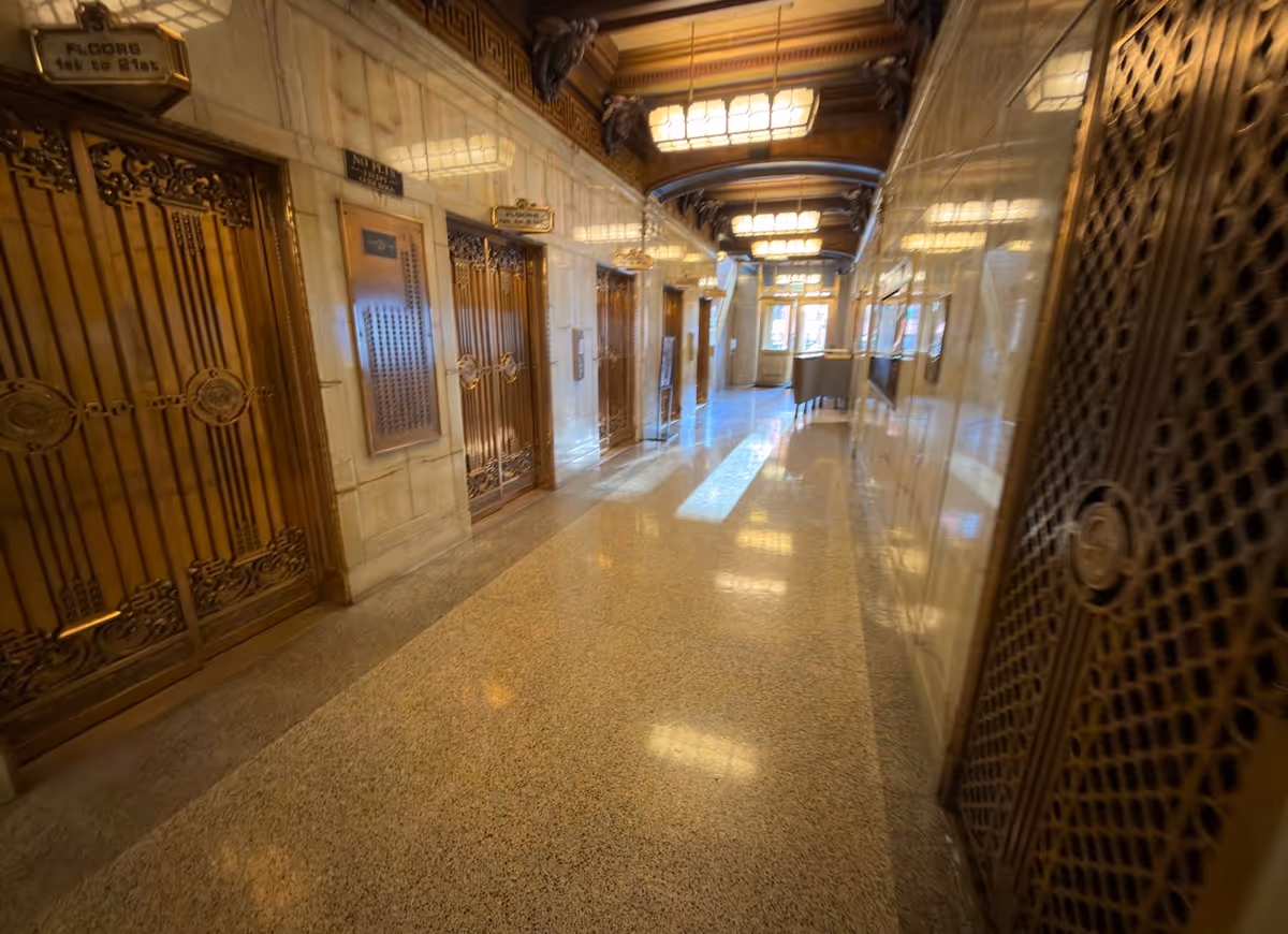 Long, polished hallway with ornate elevator doors and marble walls.