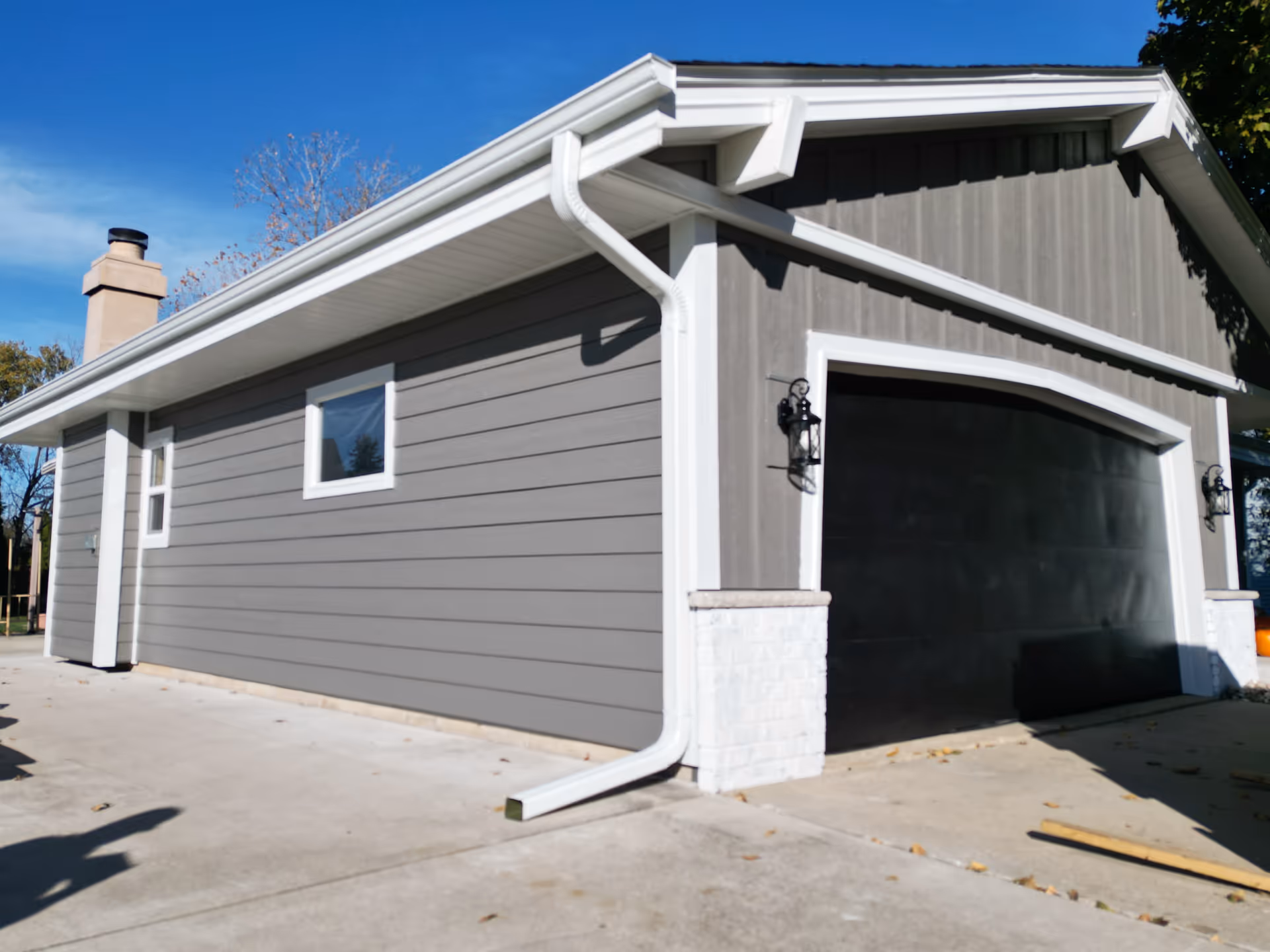 Gray siding building exterior with white trim and a large black garage door.