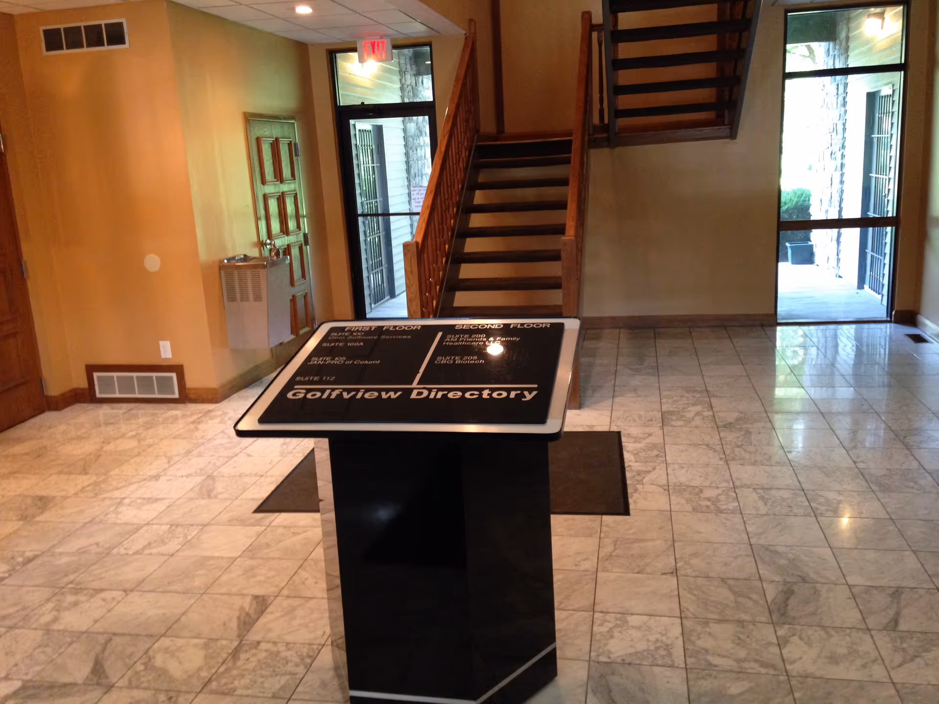 Lobby interior with a directory sign, staircase, and marble-tiled floor.