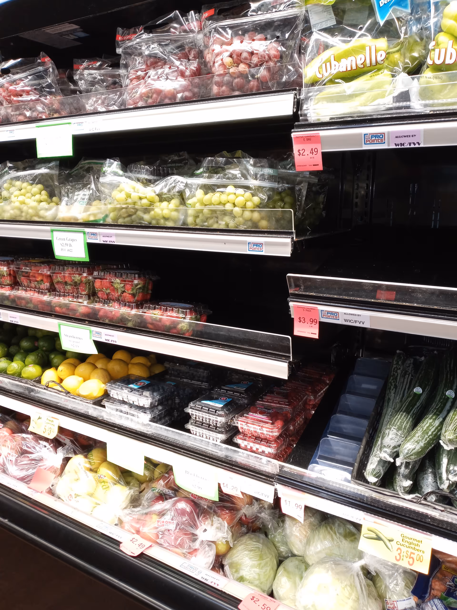 Produce section of a grocery store with bags of grapes and citrus.