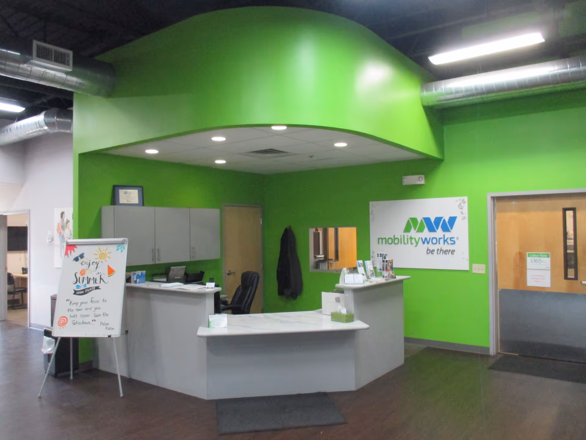 Bright green interior lobby with a reception desk and MobilityWorks signage.