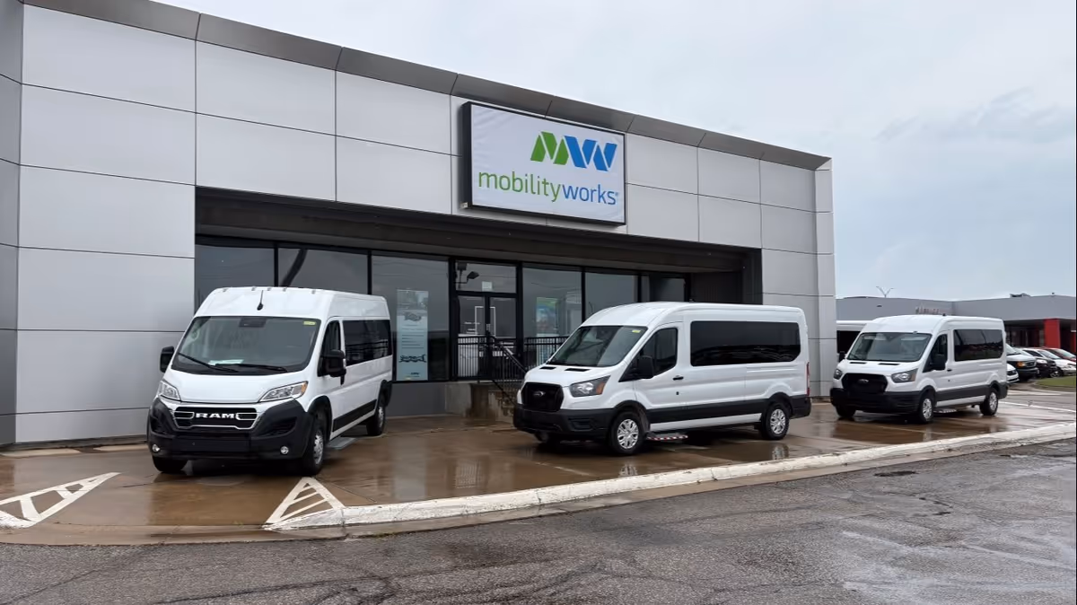 Exterior of MobilityWorks facility with three white vans parked in front of the entrance.