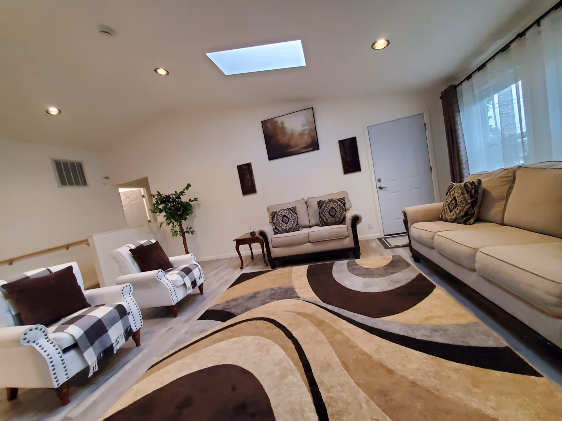 Cozy living room at JJ HAPPY ADULT FAMILY HOME with beige sofas and a patterned rug.