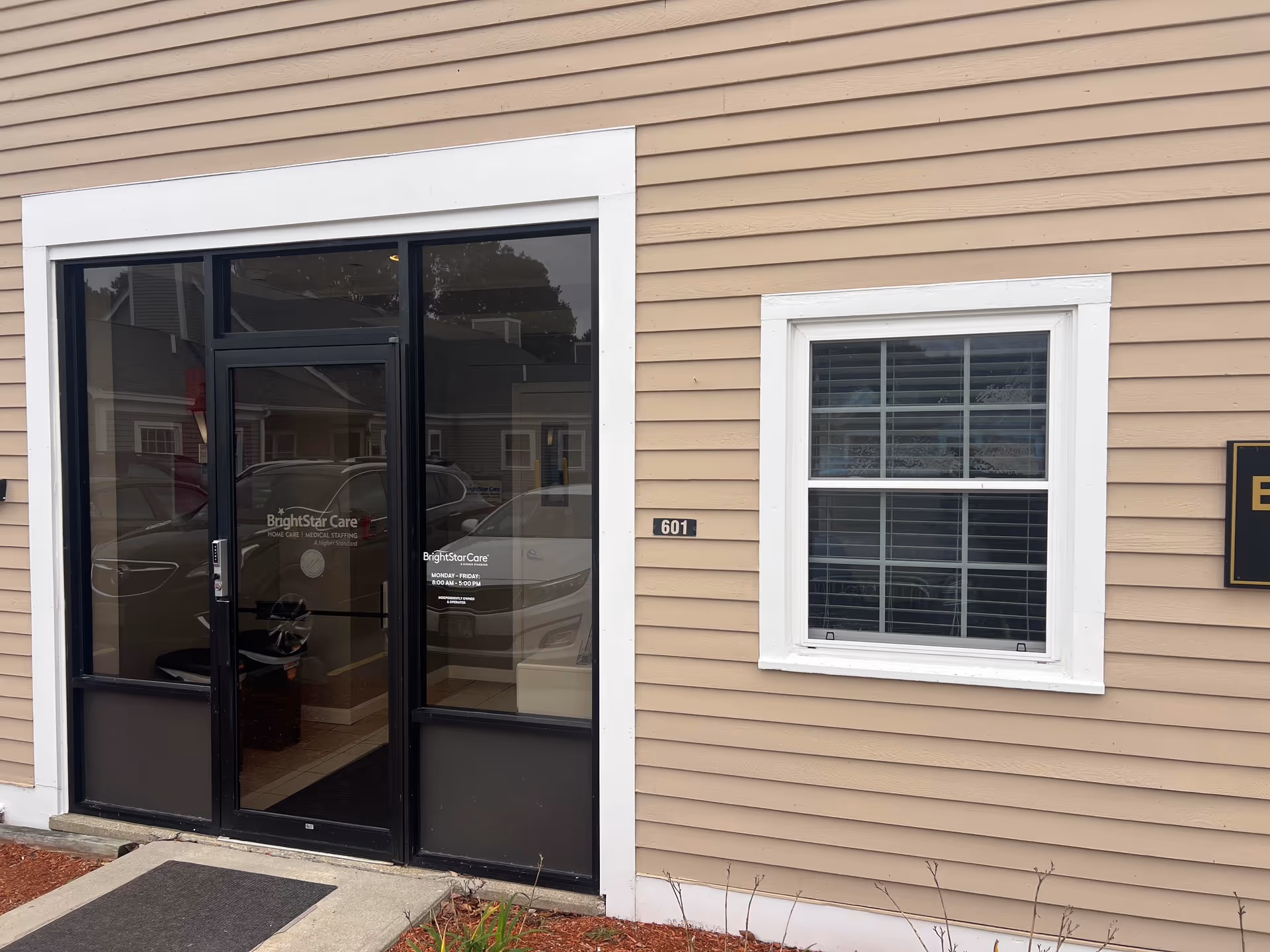 Beige exterior building with glass front doors labeled BrightStar Care and a window.