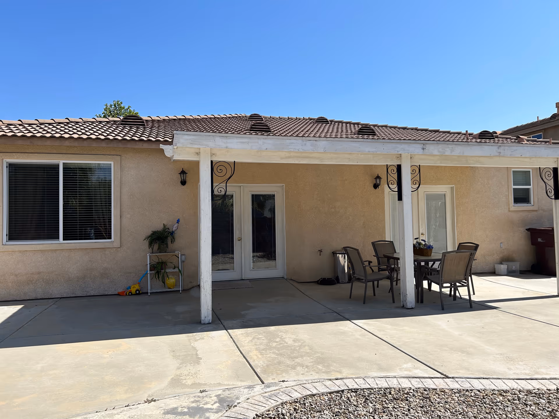 Back patio of a single-story building with a covered seating area and outdoor table.